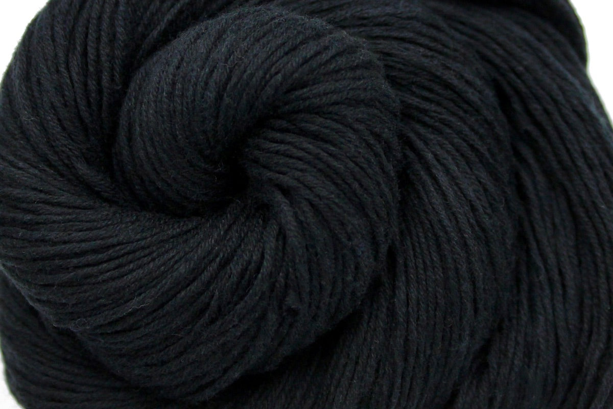 A close up shot of a skein of Vegan, Black, 100% Cotton, Fingering weight Yarn recycled by hand from unwanted sweaters beautifully coiled in the center of the frame.