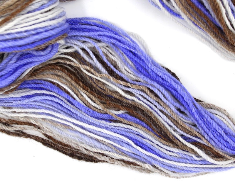 A one of a kind, hand dyed Variegated skein of multicolored Purple, Lavender, White, Tan, and Brown self-striping wool Yarn draped diagonally across the frame, so you can really see the color play.