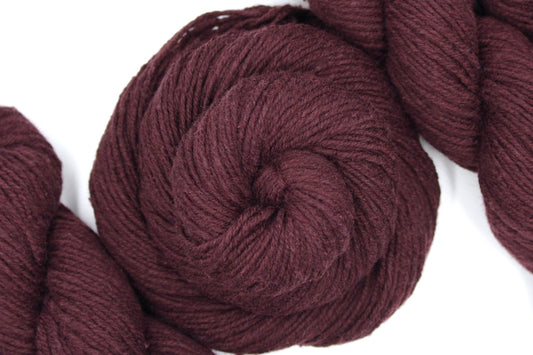 A skein of Vegan, Maroon/ Reddish Brown, Cotton/ Acrylic/ Nylon, Dk weight Yarn recycled by hand from unwanted sweaters swirled attractively in the center of the frame.