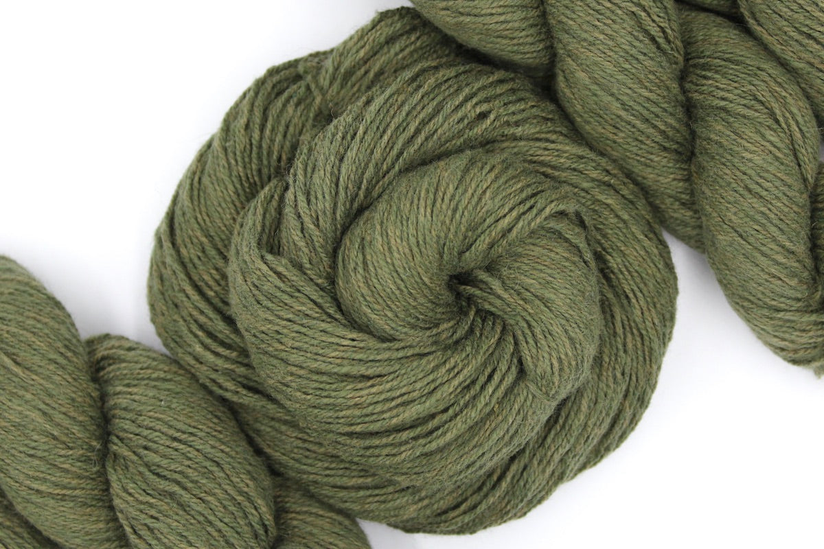 A skein of Heathered Sage, Olive Green, Cotton/ Nylon/ Wool, Sport weight Yarn recycled by hand from unwanted sweaters swirled attractively in the center of the frame.