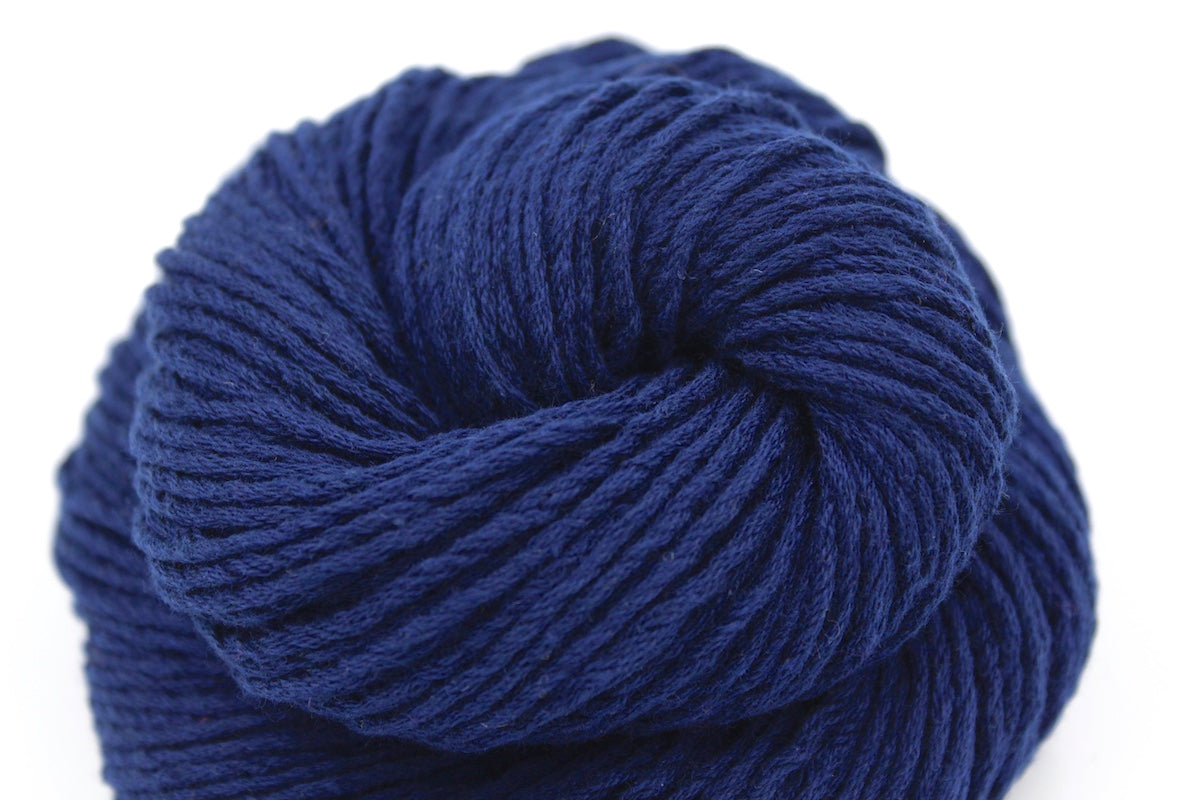 A close up shot of a skein of Vegan, Sailor Navy Blue, Cotton/ Polyester/ Acrylic, Dk weight Yarn recycled by hand from unwanted sweaters beautifully coiled in the center of the frame.