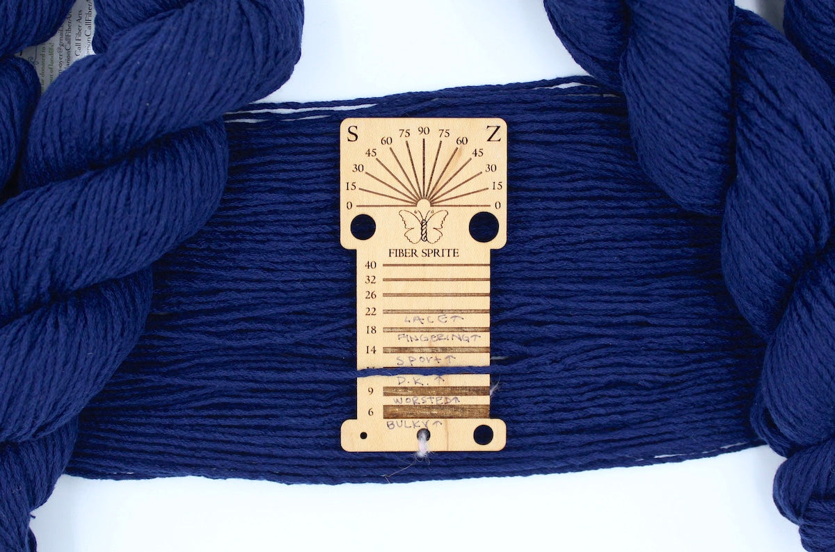 A skein of Vegan, Sailor Navy Blue, Cotton/ Polyester/ Acrylic, Dk Weight Yarn recycled by hand from unwanted sweaters draped over a Llama shaped Yarn weight tool.