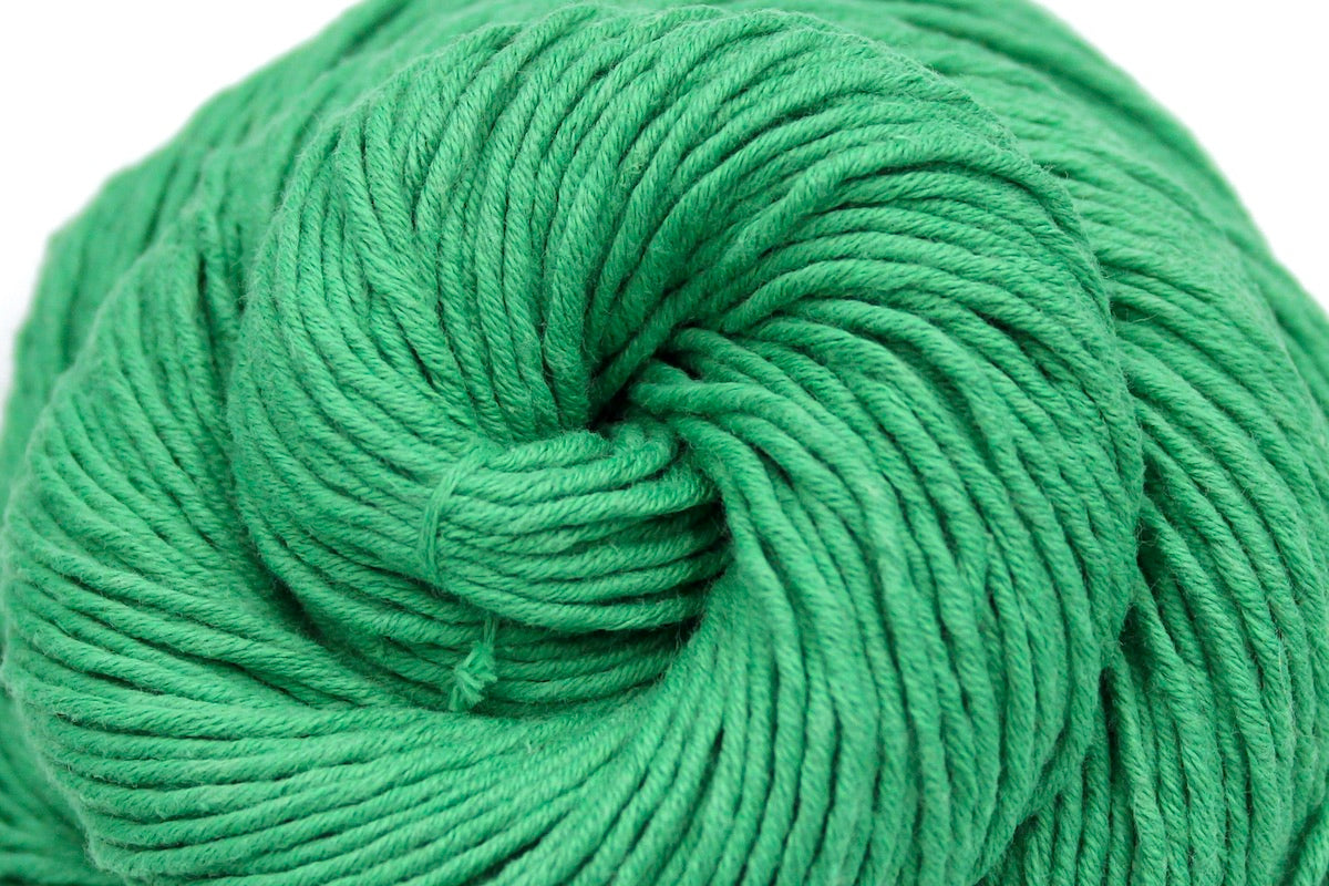A close up shot of a skein of Vegan, Bright Spearmint Green, 100% Cotton, Worsted weight Yarn recycled by hand from unwanted sweaters beautifully coiled in the center of the frame.