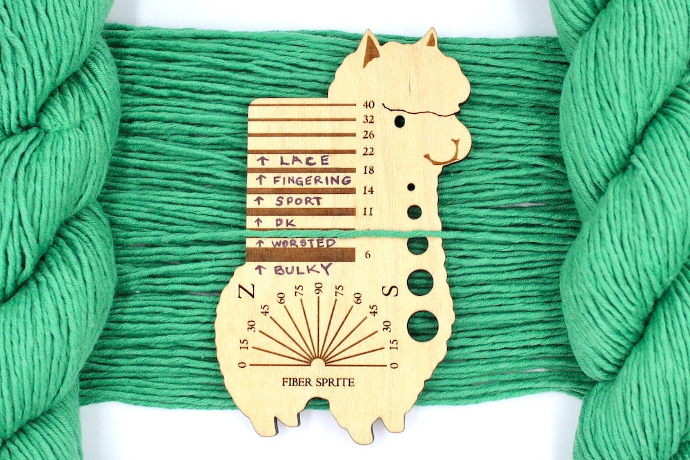 A skein of Vegan, Bright Spearmint Green, 100% Cotton, Worsted Weight Yarn recycled by hand from unwanted sweaters draped over a Llama shaped Yarn weight tool.