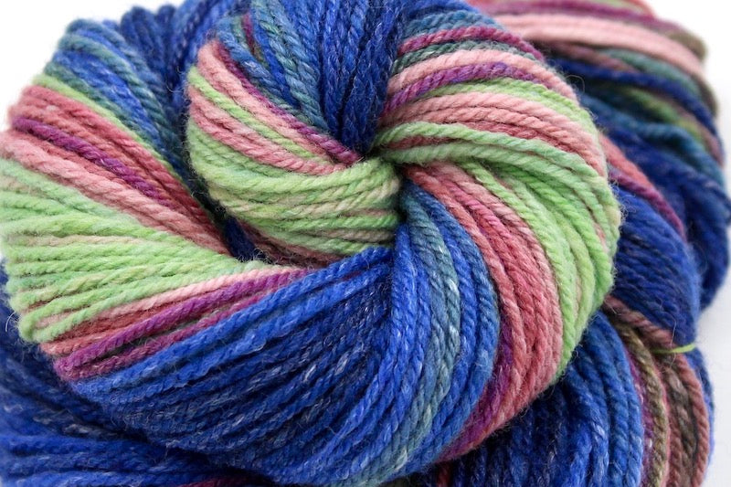 A close up view of a one of a kind, hand dyed gradient skein of multicolored Navy Blue, Royal Blue, Teal, Green, Olive Green, Magenta, Salmon, Pastel Pink and Mint Green self-striping wool Yarn.