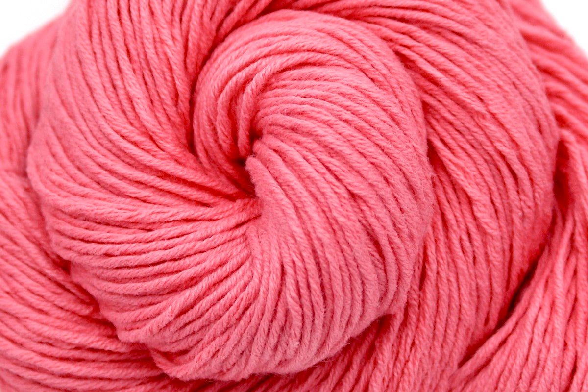 A close up shot of a skein of Vegan, Neon Rose Pink/ Fuchsia, 100% Cotton, Sport weight Yarn recycled by hand from unwanted sweaters beautifully coiled in the center of the frame.