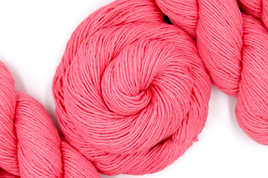 A skein of Vegan, Neon Rose Pink/ Fuchsia, 100% Cotton, Sport weight Yarn recycled by hand from unwanted sweaters swirled attractively in the center of the frame.