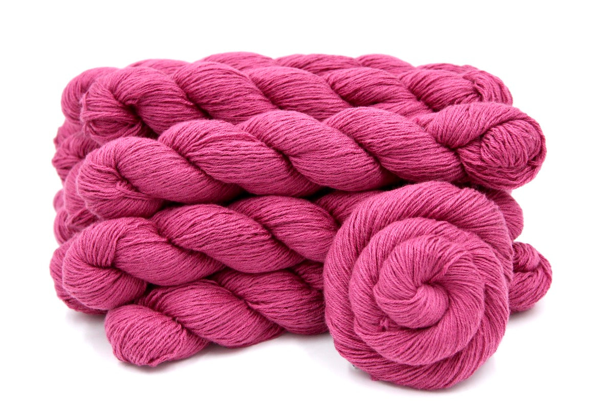 Several skeins of Vegan, Watermelon Fuchsia/ Rose Pink, Cotton/ Rayon/ Nylon, Fingering weight recycled by hand from unwanted sweaters stacked on top of each other attractively.