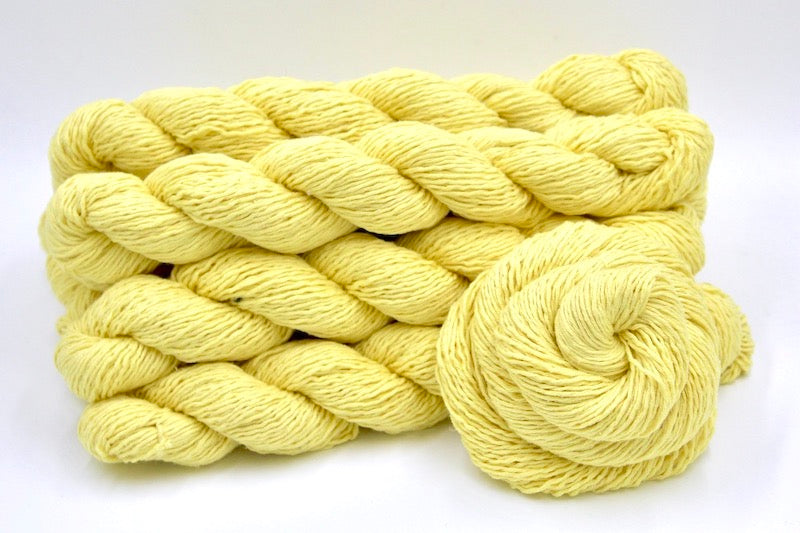 Several skeins of Bright Yellow recycled by hand from unwanted sweaters stacked on top of each other attractively