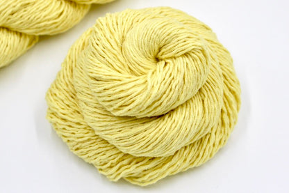 A close up shot of a skein of Bright Yellow Yarn recycled by hand from unwanted sweaters beautifully coiled in the center of the frame
