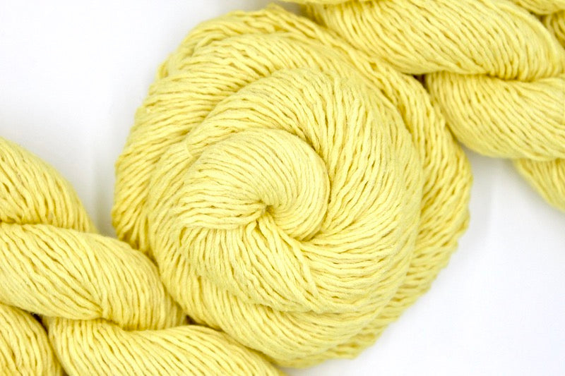 A skein of Bright Yellow Yarn recycled by hand from unwanted sweaters swirled attractively in the center of the frame