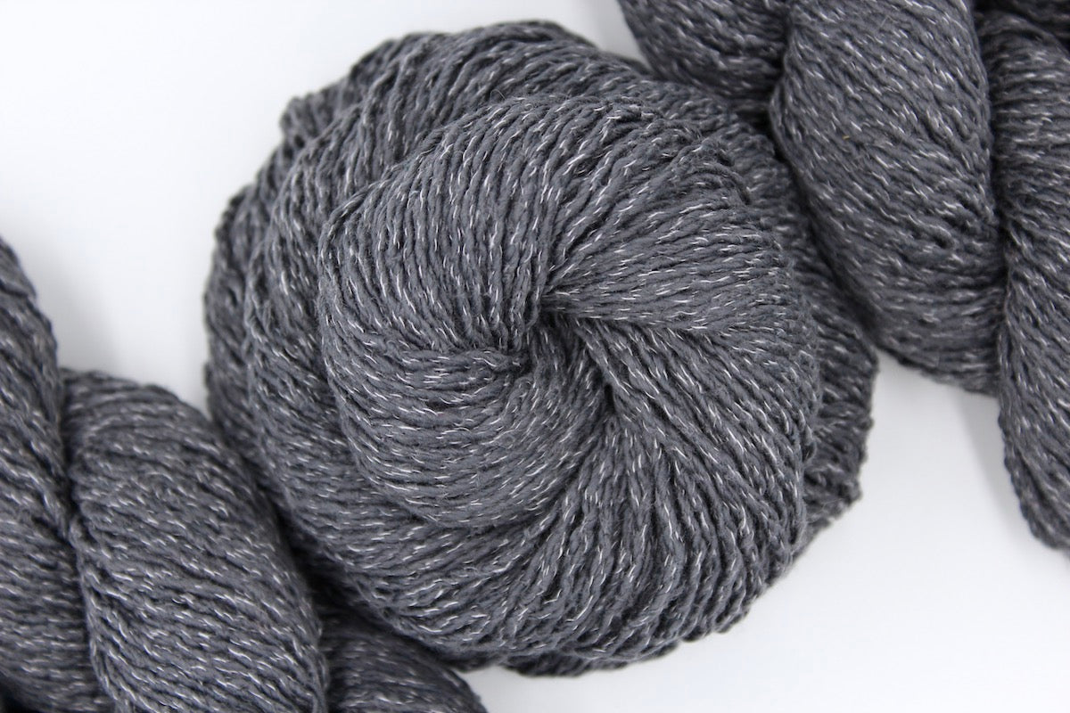 A skein of Grey Yarn recycled by hand from unwanted sweaters swirled attractively in the center of the frame