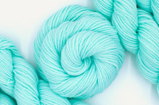 A skein of Vegan, Light Pastel Aquamarine 100% Acrylic, Worsted weight Yarn recycled by hand from unwanted sweaters swirled attractively in the center of the frame. 