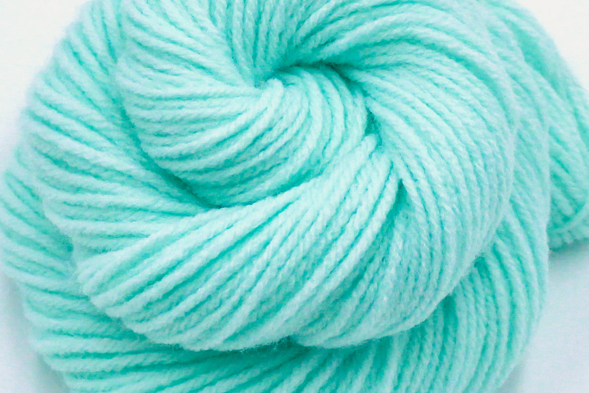 A close up shot of a skein of Vegan, Light Pastel Aquamarine 100% Acrylic, Worsted weight Yarn recycled by hand from unwanted sweaters beautifully coiled in the center of the frame. 