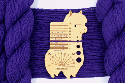 A skein of Vegan, Purple, 62% Cotton, 38% Acrylic, DK Weight Yarn recycled by hand from unwanted sweaters draped over the center of the frame with one strand on top of a Llama shaped Yarn weight tool, to better illustrate the thickness of the yarn. 