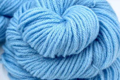 A close up shot of a skein of baby blue Yarn recycled by hand from unwanted sweaters beautifully coiled in the center of the frame