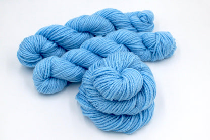 Several skeins of baby blue recycled by hand from unwanted sweaters stacked on top of each other attractively