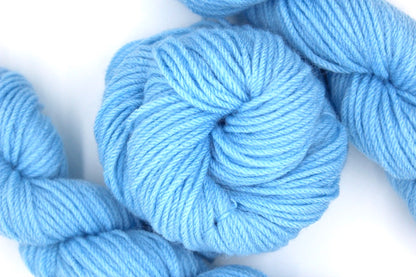 A skein of baby blue Yarn recycled by hand from unwanted sweaters swirled attractively in the center of the frame