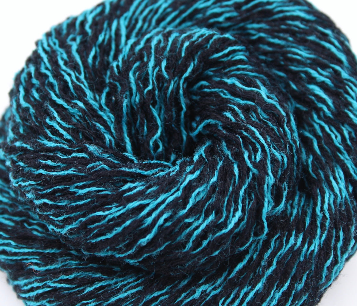 A close up shot of a skein of black and blue sport weight Yarn recycled by hand from unwanted sweaters beautifully coiled in the center of the frame.
