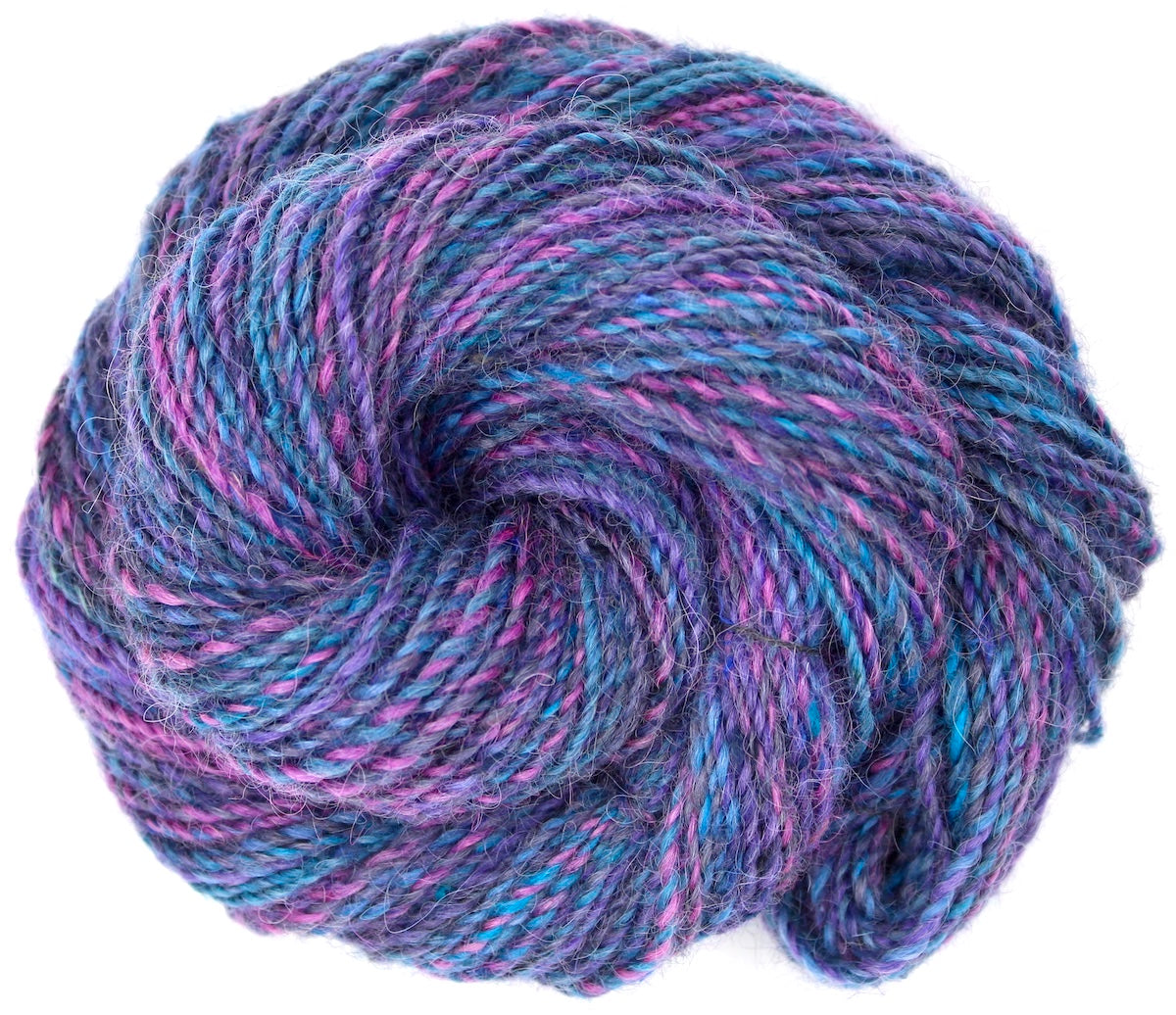 A one of a kind, hand dyed Variegated skein of multicolored Hot Pink, Blue, and Purple self-striping wool Yarn coiled attractively in the center of the frame. 