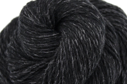 A close up shot of a skein of black and grey, DK weight Yarn recycled by hand from unwanted sweaters beautifully coiled in the center of the frame. 