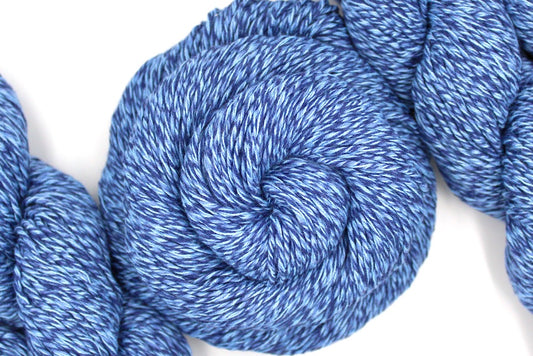 A skein of Blue Variegated, Worsted weight Yarn recycled by hand from unwanted sweaters swirled attractively in the center of the frame. 