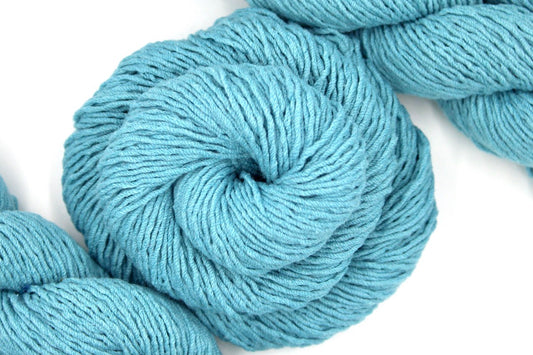 A skein of Light Blue, Dk weight Yarn recycled by hand from unwanted sweaters swirled attractively in the center of the frame. 