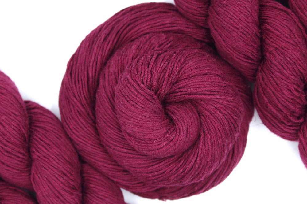 A skein of Maroon, Fingering weight Yarn recycled by hand from unwanted sweaters swirled attractively in the center of the frame. 