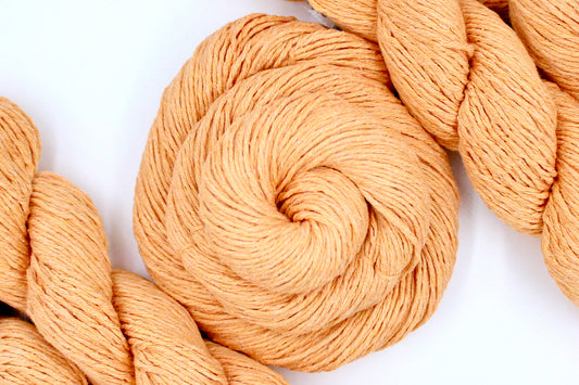 Close-up of peach-colored yarn skeins on a white background