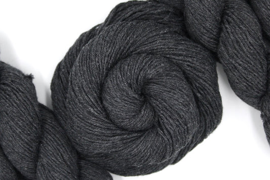 A skein of Dark Grey, Fingering weight Yarn recycled by hand from unwanted sweaters swirled attractively in the center of the frame. 