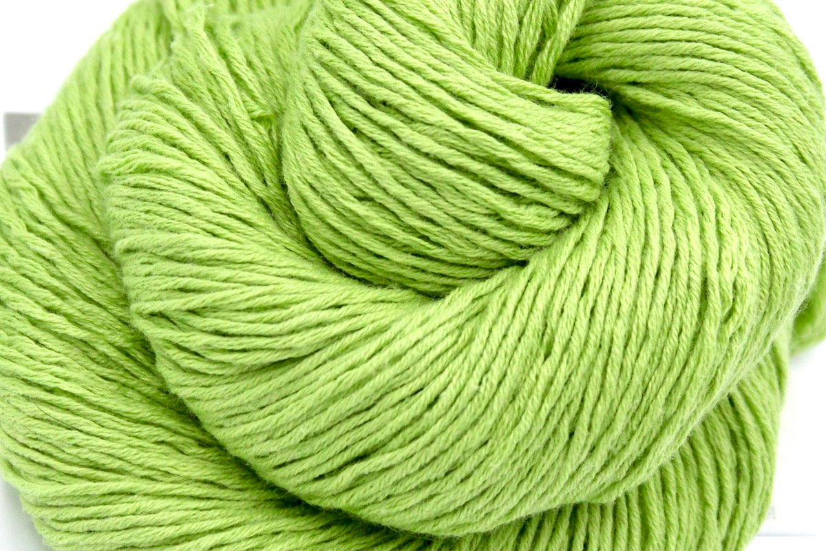 A close up shot of a skein of Lime Green, Fingering weight Yarn recycled by hand from unwanted sweaters beautifully coiled in the center of the frame. 