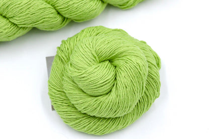 A skein of Lime Green, Fingering weight Yarn recycled by hand from unwanted sweaters swirled attractively in the center of the frame. 