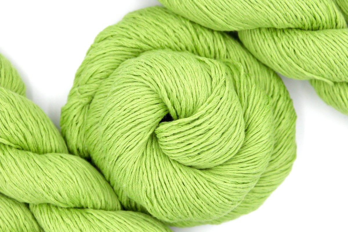 A skein of Lime Green, Fingering weight Yarn recycled by hand from unwanted sweaters swirled attractively in the center of the frame. 