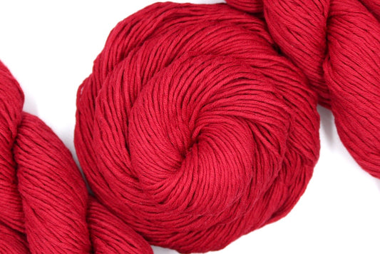 A skein of Ruby Red, Dk weight Yarn recycled by hand from unwanted sweaters swirled attractively in the center of the frame. 