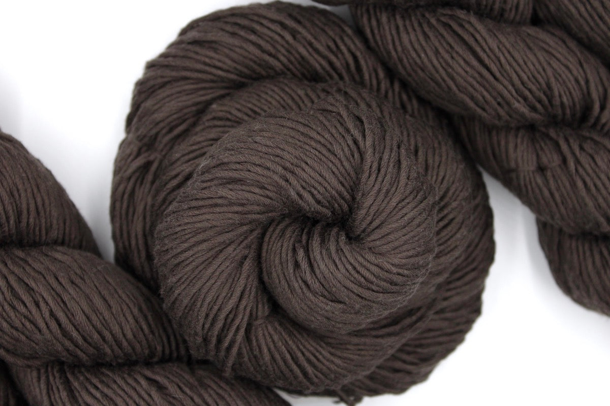 A skein of Vegan, Dark Chocolate Brown, 100% Upcycled Cotton, Heavy Worsted (or Aran) Weight Yarn recycled by hand from unwanted sweaters swirled attractively in the center of the frame. 
