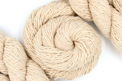 A skein of Beige or Cream, 90% Upcycled Acrylic, 10% Wool, Heavy Worsted (or Aran) Weight Yarn recycled by hand from unwanted sweaters swirled attractively in the center of the frame. 