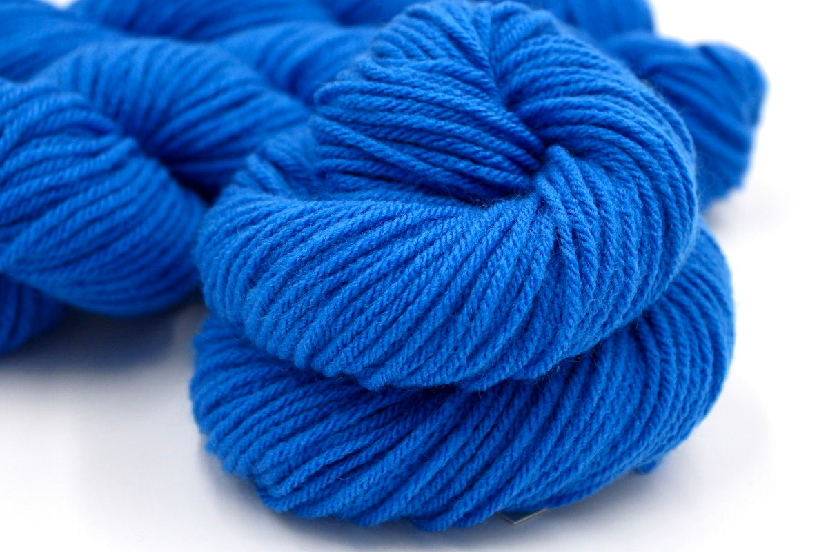 A close up shot of a skein of Royal Blue, Worsted weight Yarn recycled by hand from unwanted sweaters beautifully coiled in the center of the frame. 