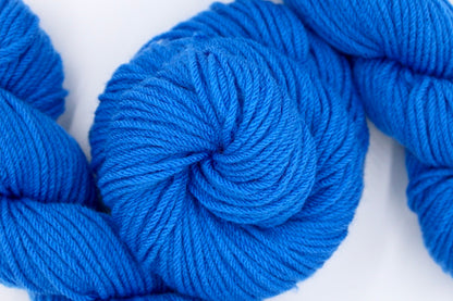 A skein of Royal Blue, Worsted weight Yarn recycled by hand from unwanted sweaters swirled attractively in the center of the frame. 