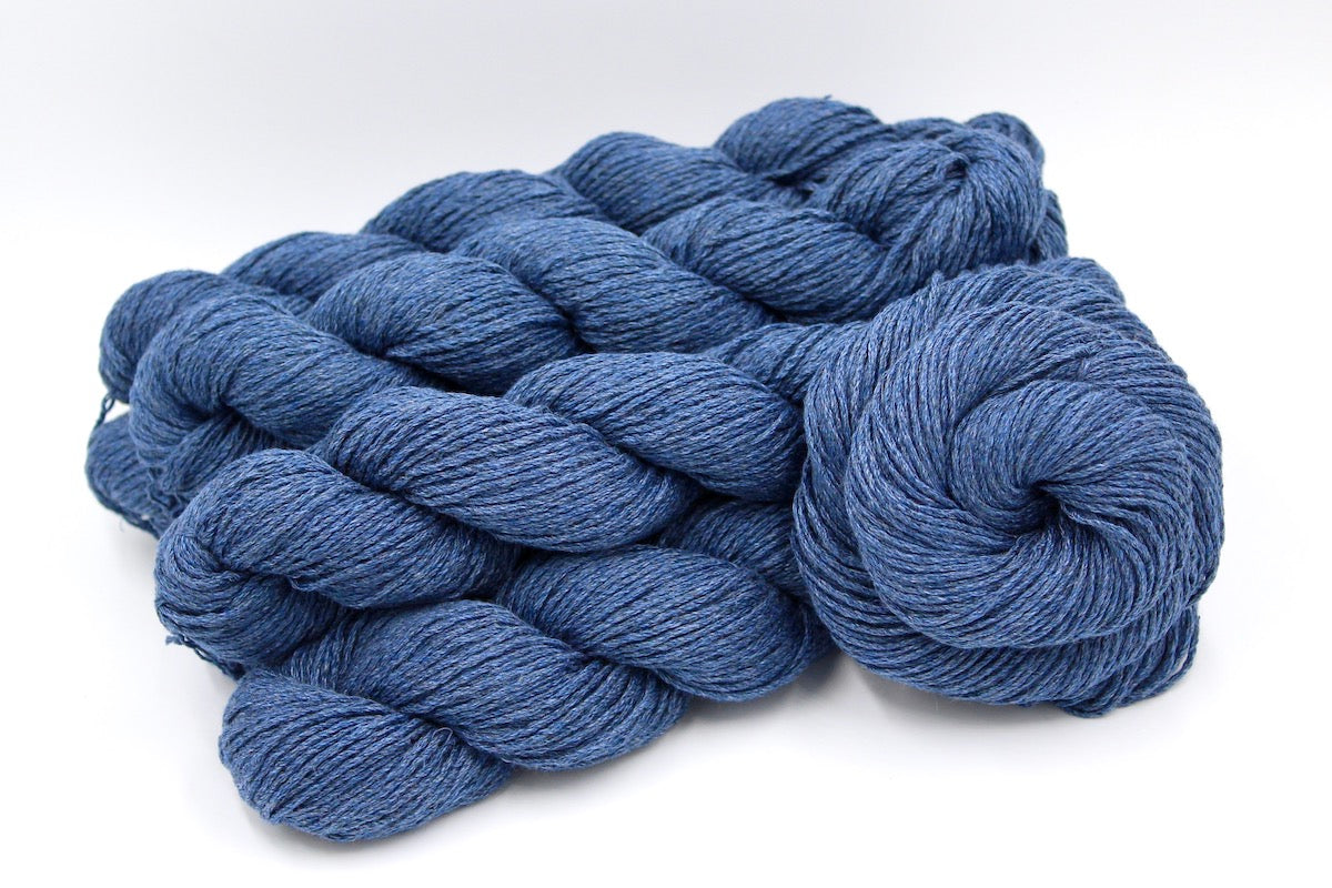 Several skeins of Cornflower Blue, Dk weight recycled by hand from unwanted sweaters stacked on top of each other attractively. 