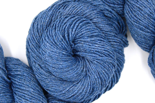 A skein of Cornflower Blue, Dk weight Yarn recycled by hand from unwanted sweaters swirled attractively in the center of the frame.