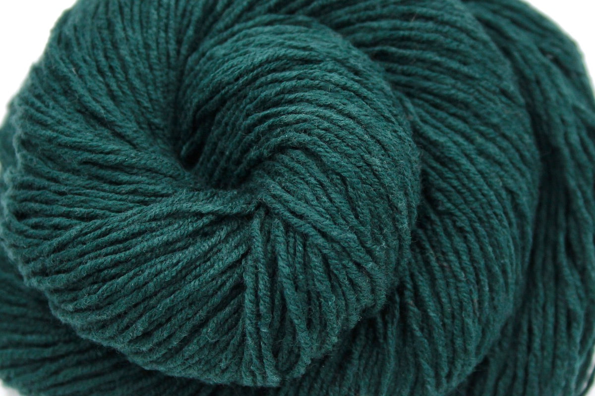 A close up shot of a skein of Dark Forest green, Fingering weight Yarn recycled by hand from unwanted sweaters beautifully coiled in the center of the frame. 