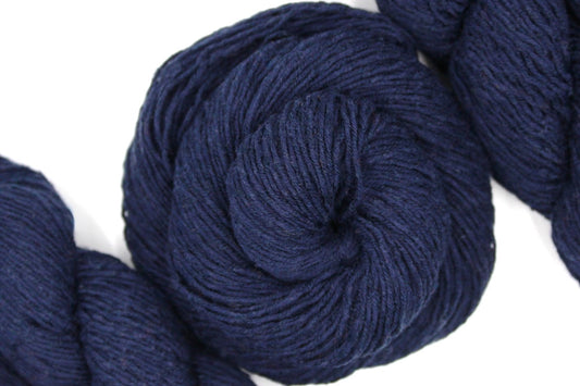 A skein of Dark Navy Blue, Fingering weight Yarn recycled by hand from unwanted sweaters swirled attractively in the center of the frame. 