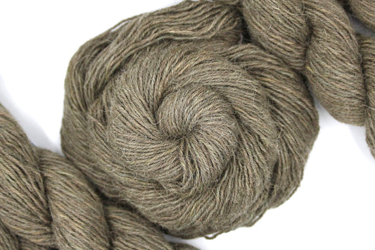 A skein of Natural Alpaca, Fingering weight Yarn recycled by hand from unwanted sweaters swirled attractively in the center of the frame. 
