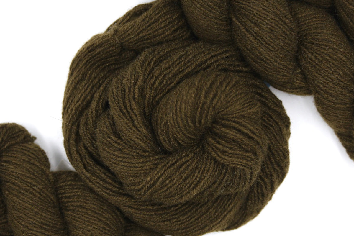A skein of Dark Olive Cashmere, Fingering weight Yarn recycled by hand from unwanted sweaters swirled attractively in the center of the frame. 