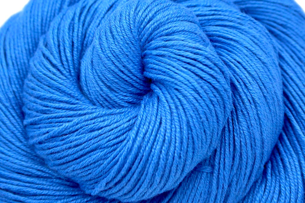 A close up shot of a skein of Baby Blue, Cotton Rayon Nylon, Fingering weight Yarn recycled by hand from unwanted sweaters beautifully coiled in the center of the frame. 