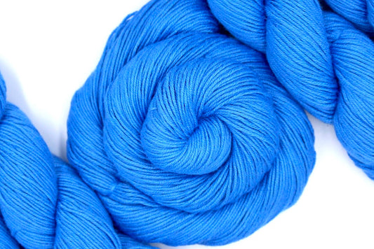 A skein of Baby Blue, Cotton Rayon Nylon, Fingering weight Yarn recycled by hand from unwanted sweaters swirled attractively in the center of the frame. 