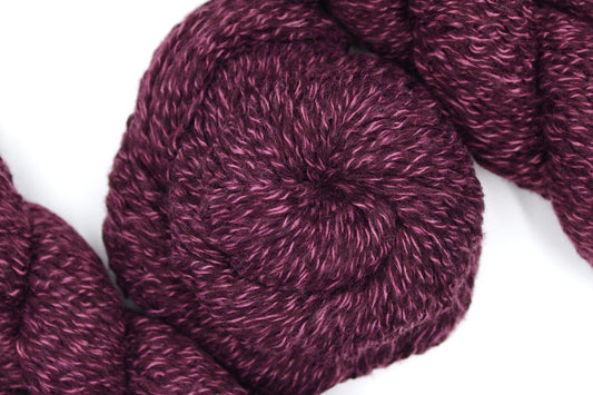 A skein of Heathered Purple, 100% Acrylic, Worsted weight Yarn recycled by hand from unwanted sweaters swirled attractively in the center of the frame. 