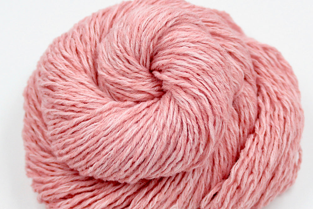A close up shot of a skein of Vegan, Pink, 60% Cotton, 40% Acrylic, Dk Weight Yarn recycled by hand from unwanted sweaters beautifully coiled in the center of the frame. 