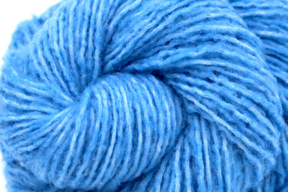 A close up shot of a skein of Light Baby Blue, Acrylic, Nylon, Wool, Cashmere, Dk weight Yarn recycled by hand from unwanted sweaters beautifully coiled in the center of the frame. 