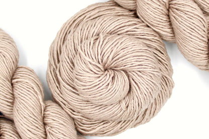 A skein of Tan, 40% Wool, 30% Nylon, 30% Modal, Worsted Weight Yarn recycled by hand from unwanted sweaters swirled attractively in the center of the frame. 